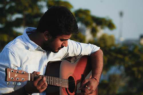 musical instrument man in white shirt playing acoustic guitar guitar